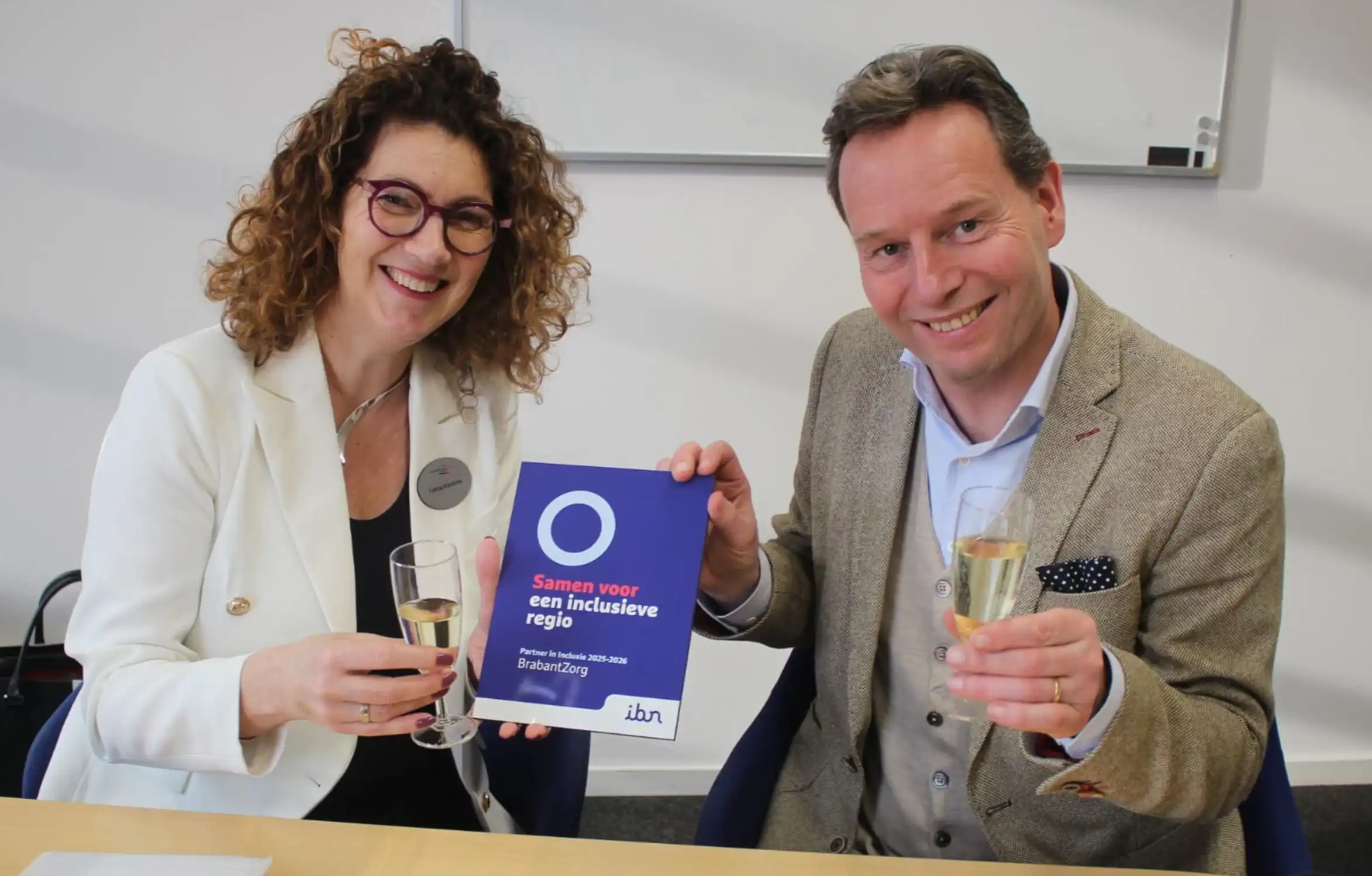 Het schildje Partner in Inclusie wordt aan BrabantZorg overhandigd