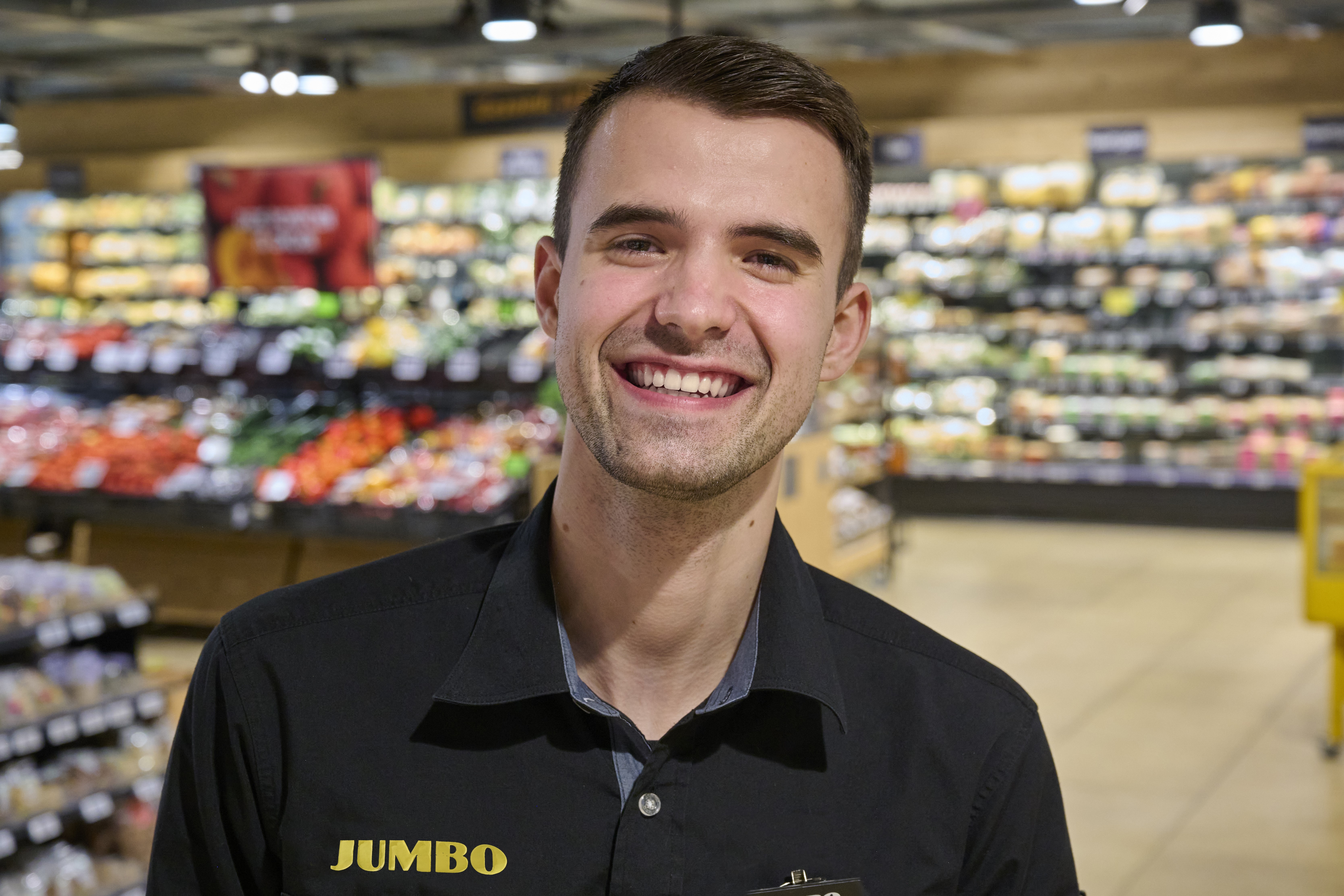 Thomas stralend op zijn werkplek in de Jumbo