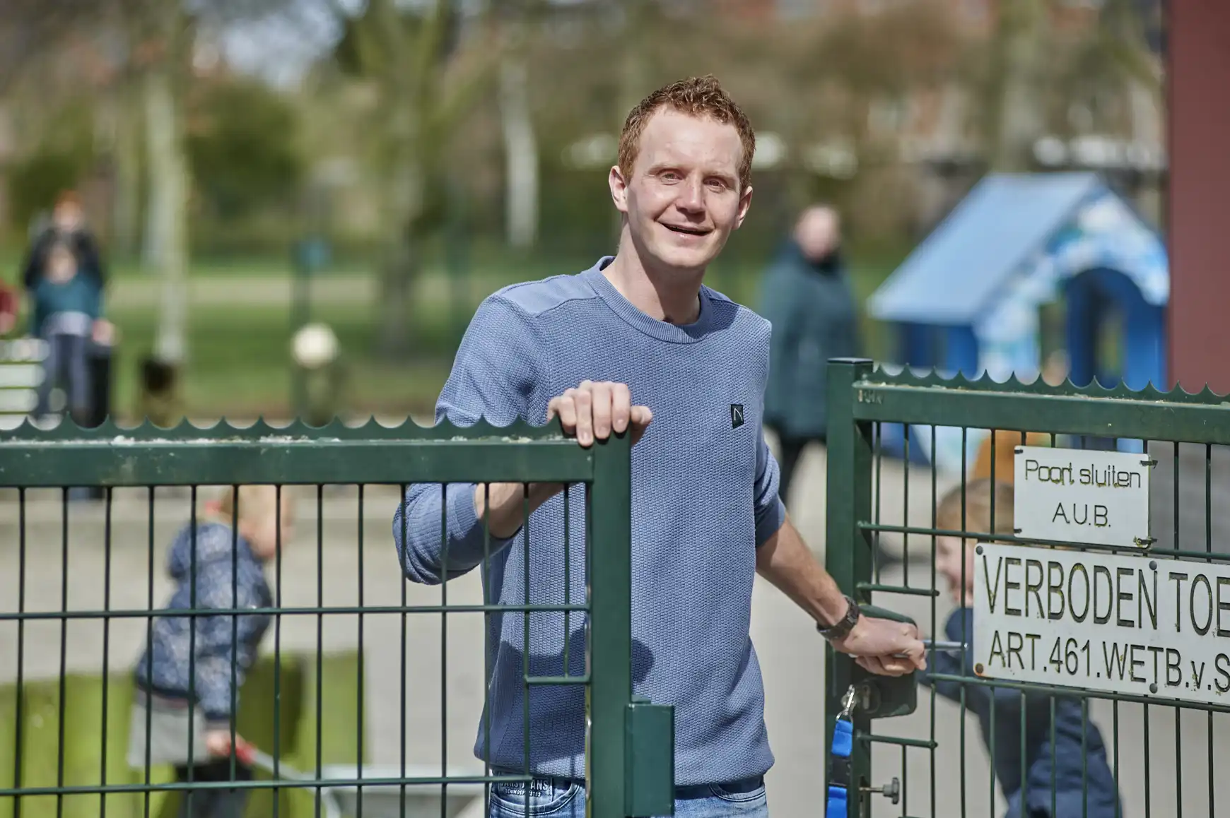 Tim bij het hek van de school waar hij als conciërge werkt