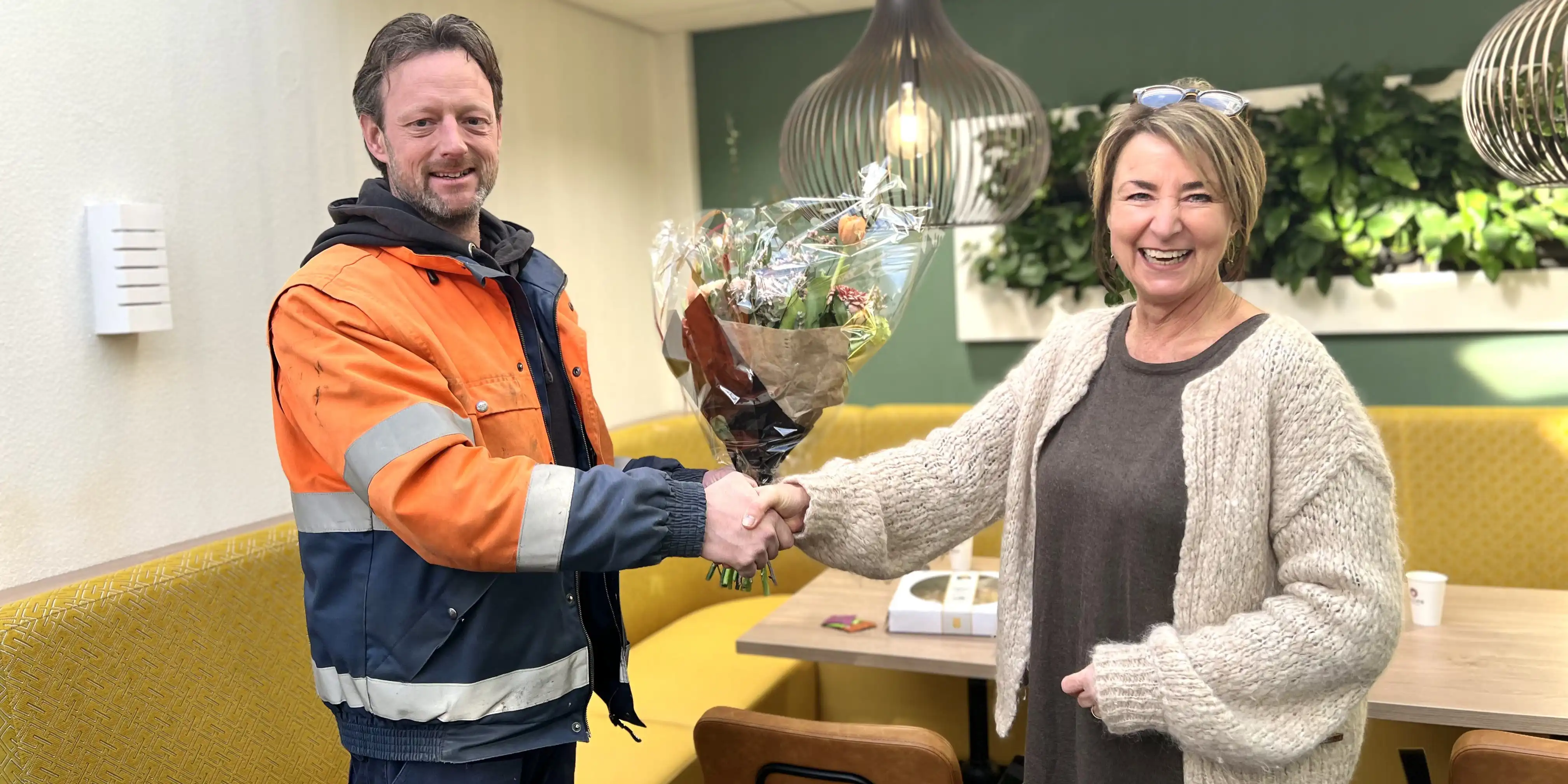 Anna overhandigt Rob een bos bloemen op zijn nominatie te vieren.