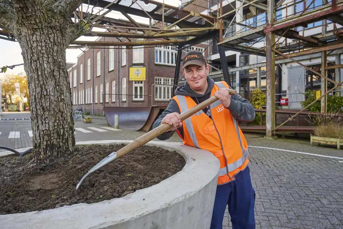 Kevin medewerker groen met de hark in zijn handen.