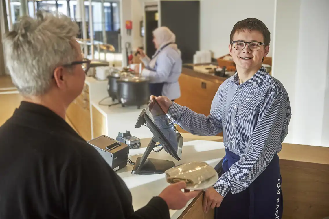 Noah Slegers achter de kassa op zijn werkplek