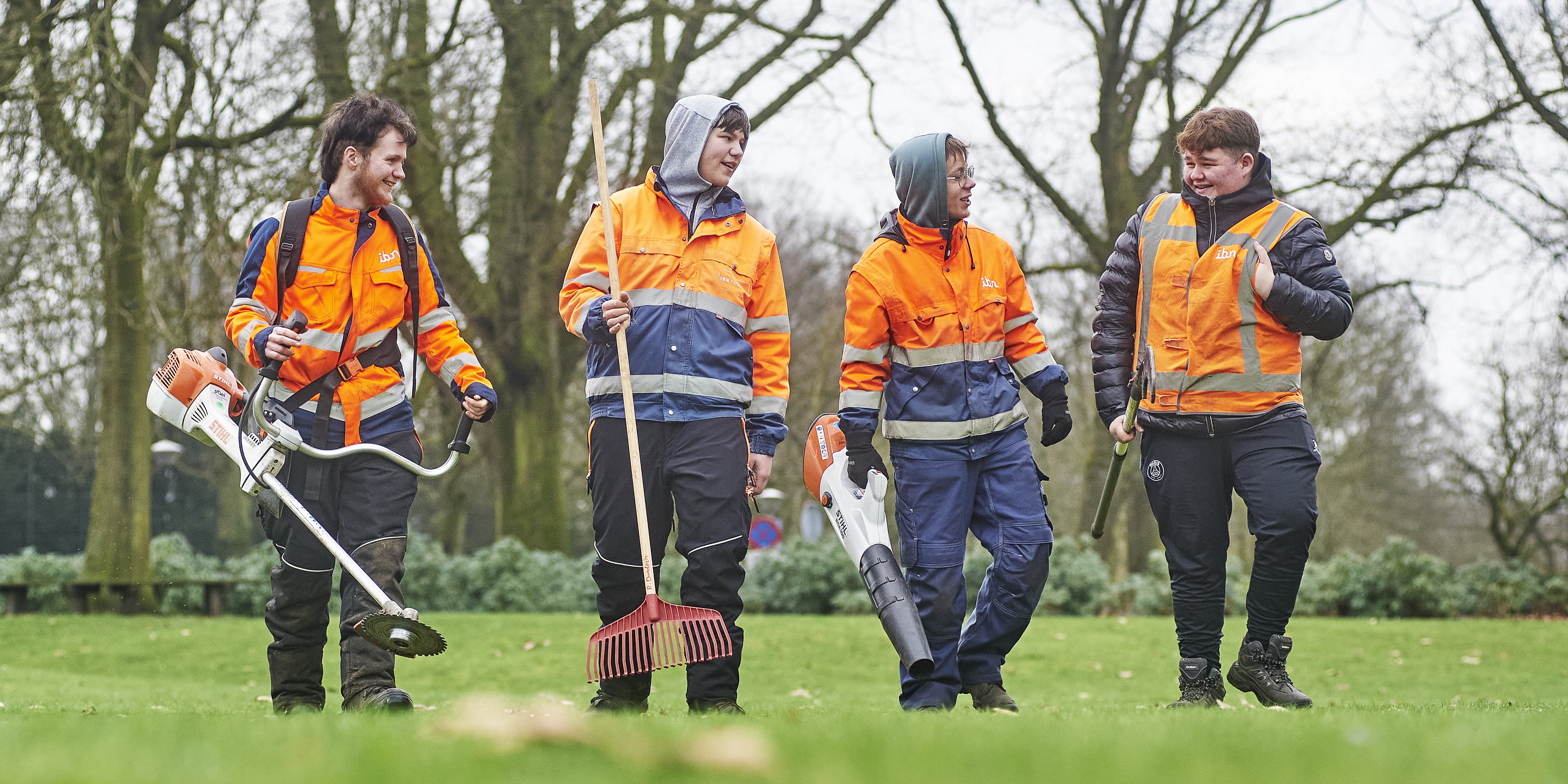 vier jongeren lopend in het groen met machines en gereedschap in hun handen