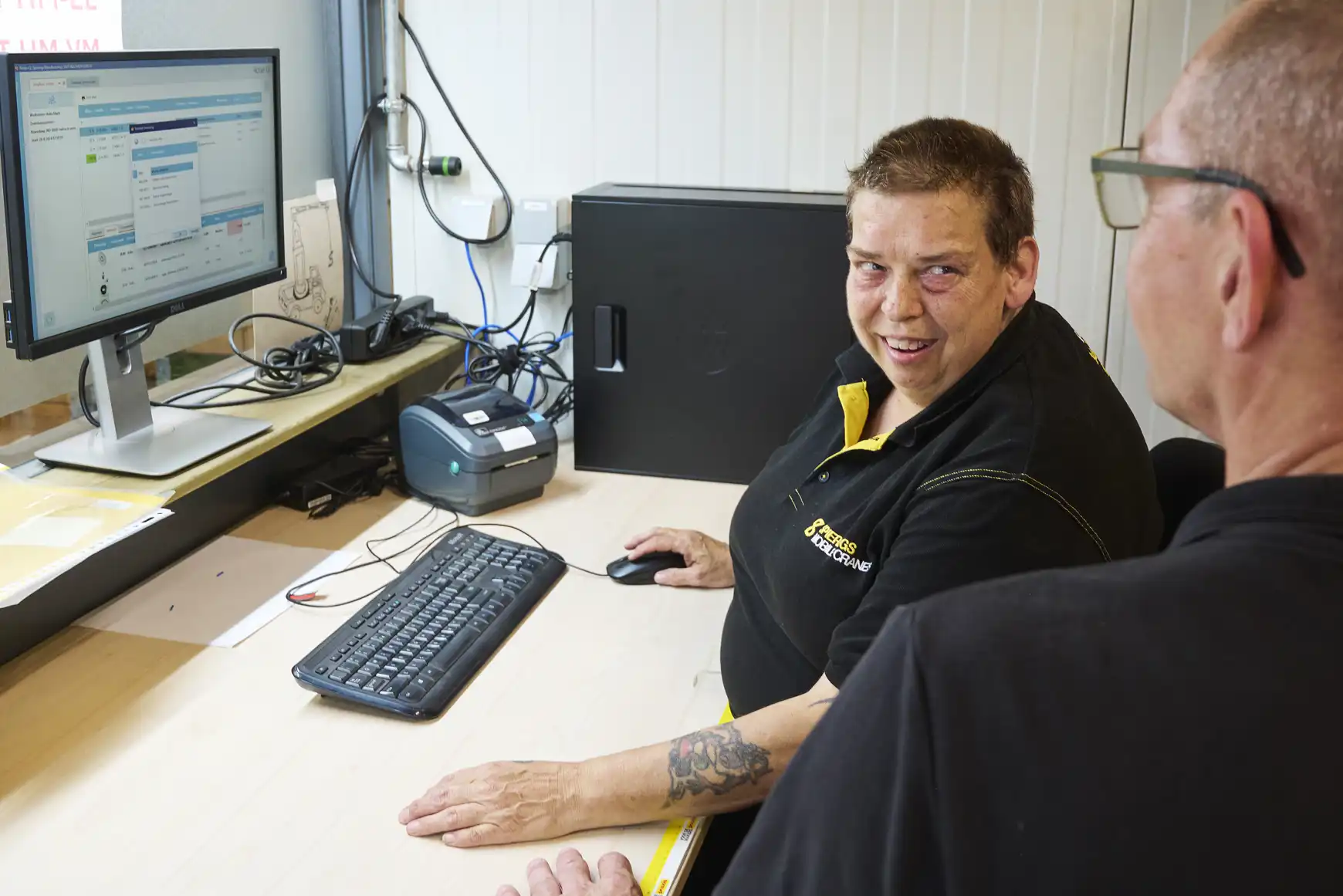 Anita in gesprek met haar collega achter de computer