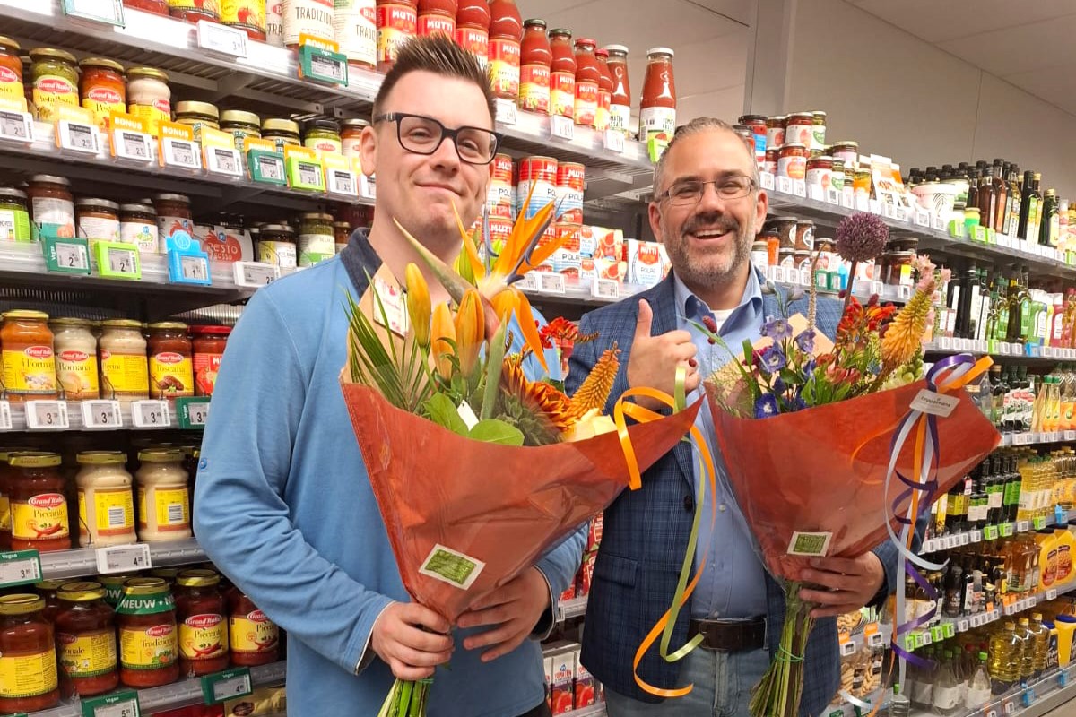 Joël met een bos bloemen op zijn werkplek bij de Albert Heijn